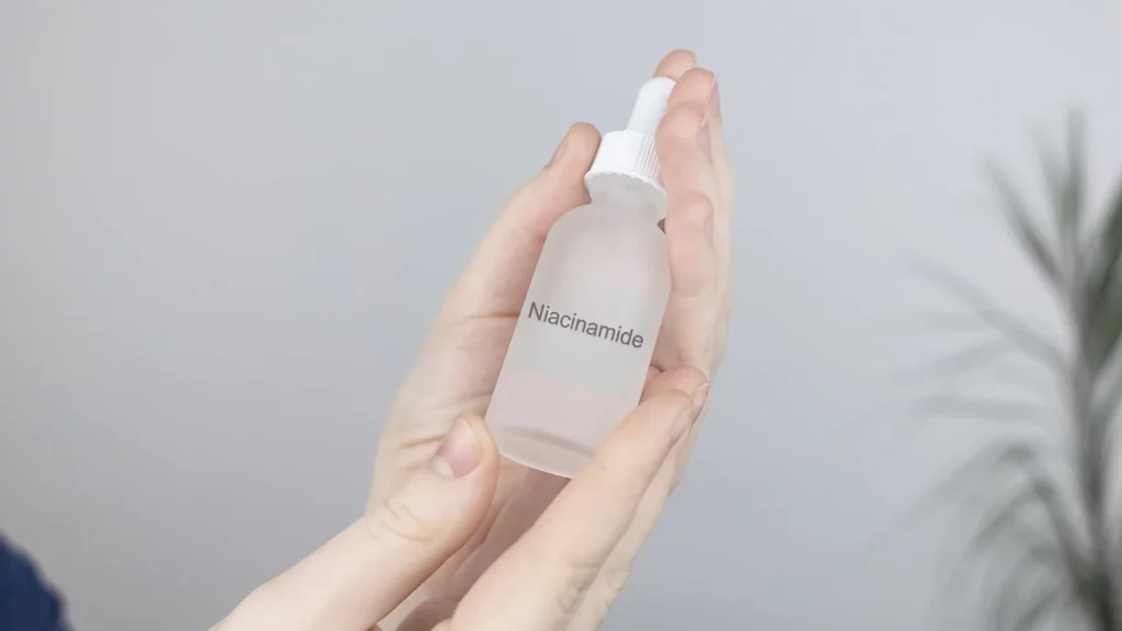 Kobieta trzyma w dłoniach buteleczkę z serum z niacynamidem
