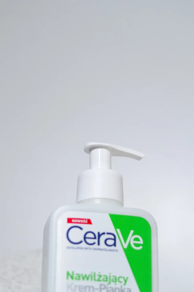 Butelka CeraVe z pompką stoi na blacie, minimalistyczne jasne tło i miękka perspektywa.