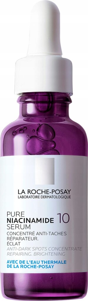 Fioletowa szklana butelka serum z białą pipetą stoi pionowo, widoczna etykieta La Roche-Posay.