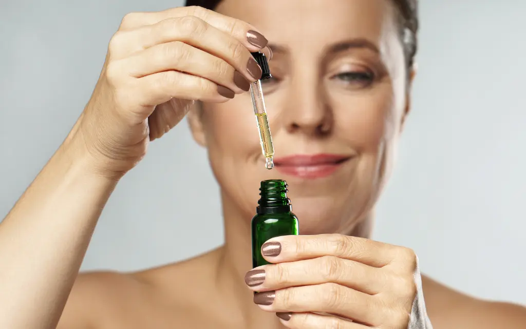 Uśmiechnięta kobieta trzyma buteleczkę serum z probiotykami 