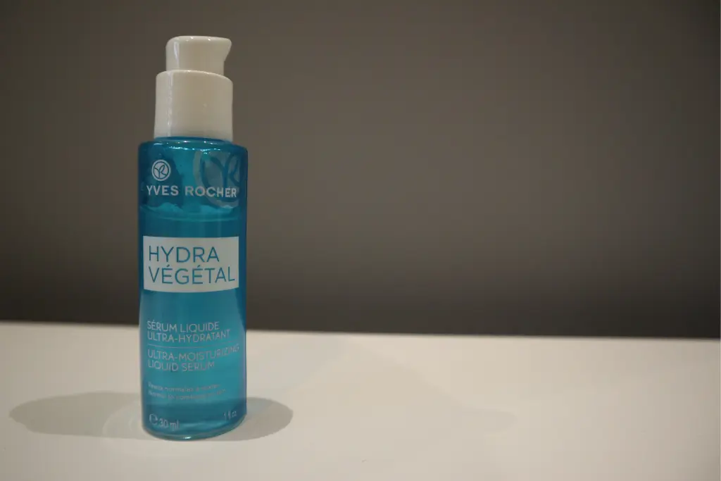 Niebieska buteleczka serum Hydra Végétal stoi na białej powierzchni przed szarym tłem.