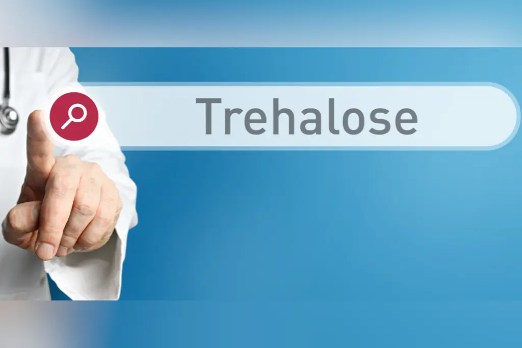 Dłoń mężczyzny w białym fartuchu pokazuje lupkę i obok napis trehaloza na niebieskim tle