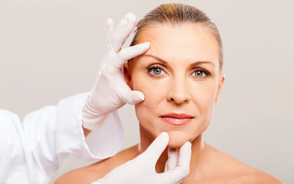 Dermatolog w rękawiczkach ocenia stan cery dojrzałej u pacjentki 