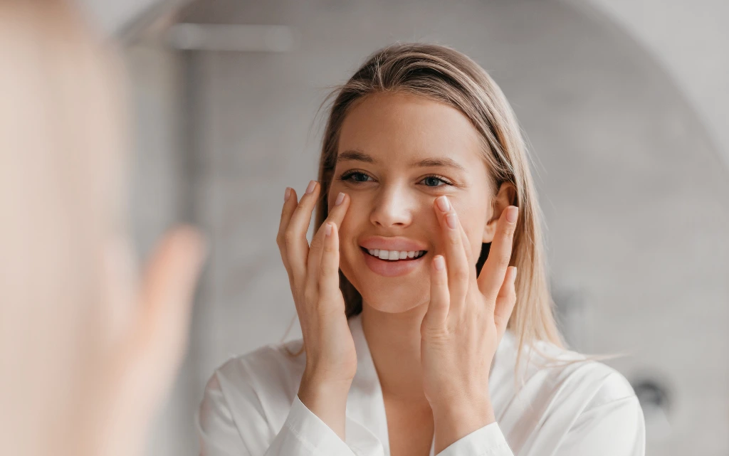 Młoda kobieta przed lustrem nakłada serum do cery normalnej