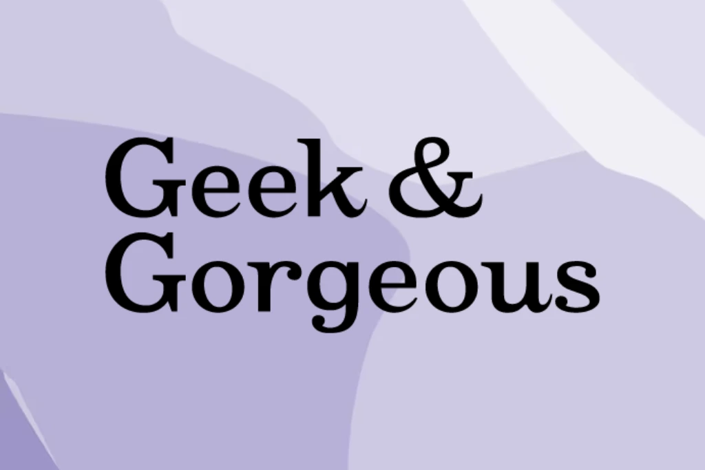 Napis "Geek & Gorgeous" umieszczony na abstrakcyjnym, falistym liliowym tle, czarna ozdobna czcionka.