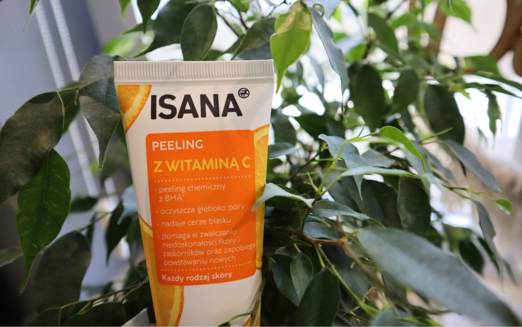  ISANA, peeling do twarzy, z witaminą C na tle zielonego kwiatka 