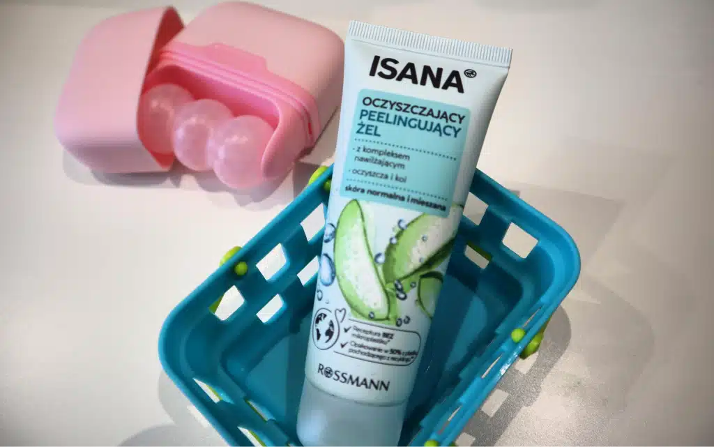 ISANA Żel peeling, oczyszczający w małym, niebieskim koszyczku, w tle rolka masująca 