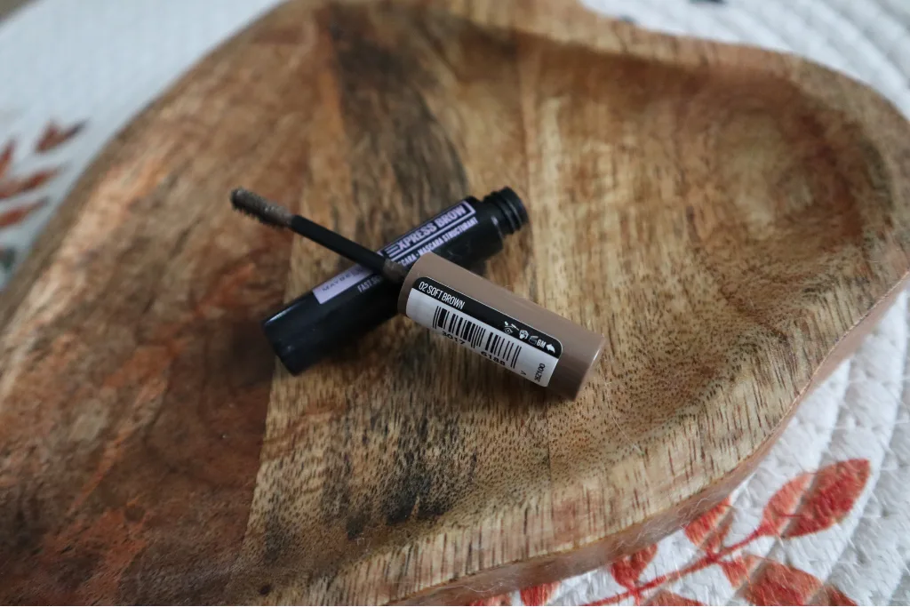 Szczoteczka maskary do brwi Maybelline NY Express brow Sculpt na brązowym tle