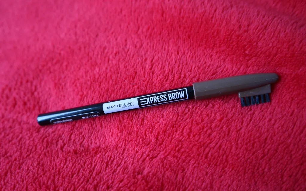Kredka do brwi Maybelline NY Express Brow Shaping Pencil na tle czerwonego kocyka