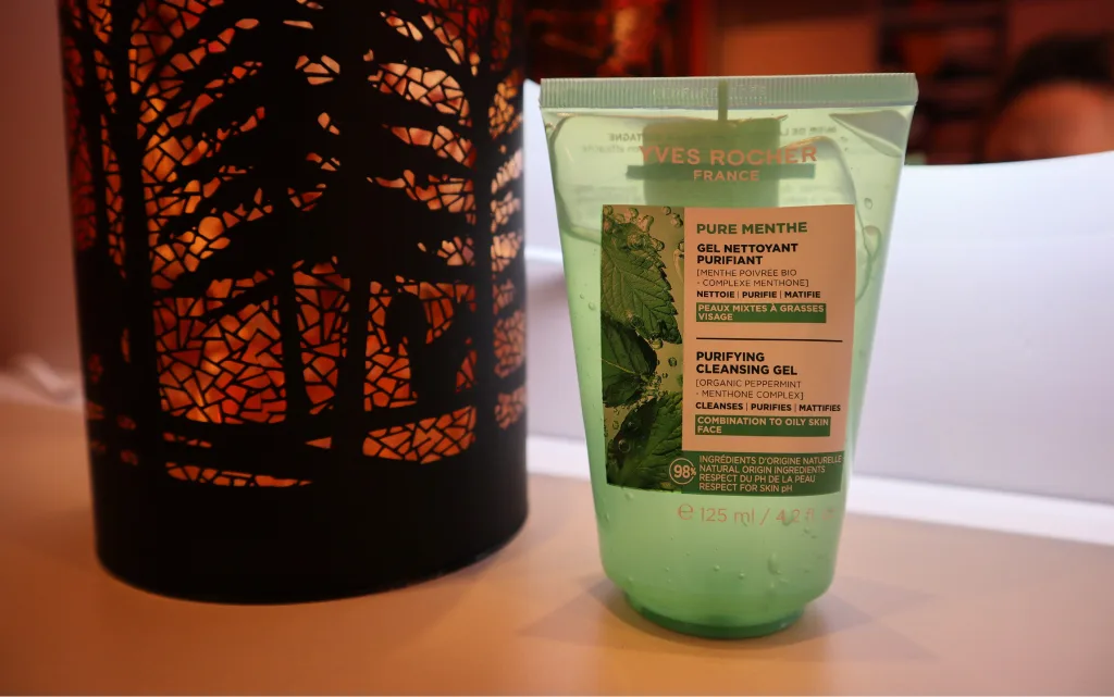 Yves Rocher żel oczyszczający z miętą pieprzową stojący obok jesiennej lampki 