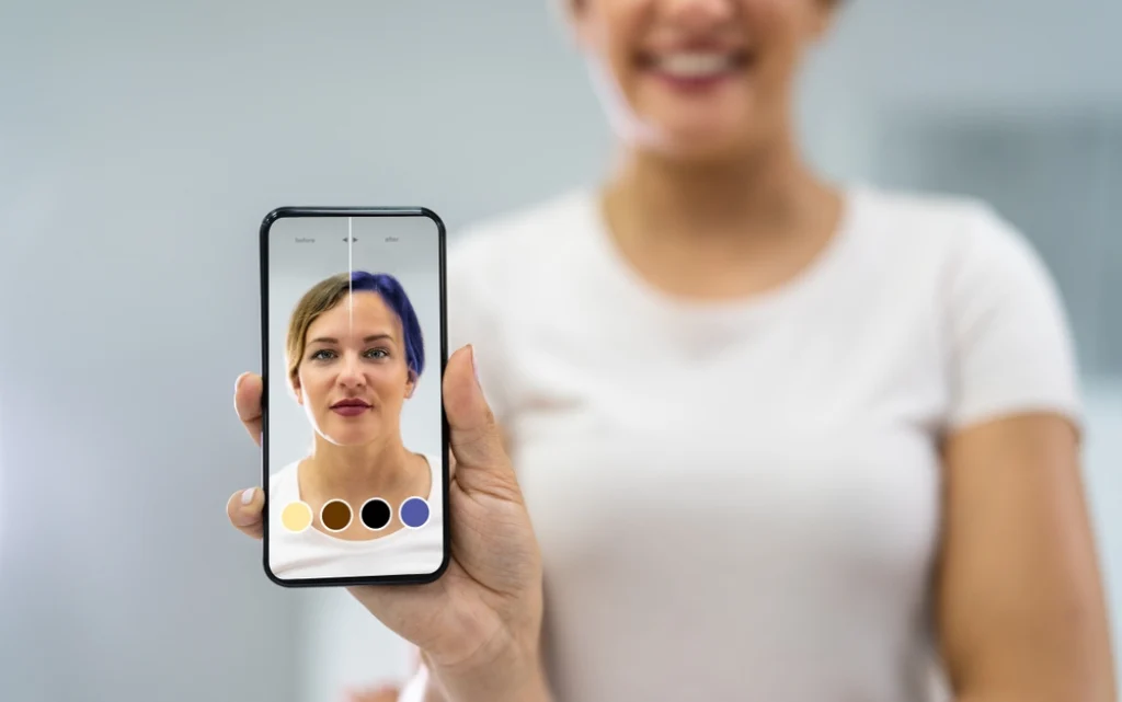 Kobieta pokazuje smartfon z aplikacją  wirtualnego makijażu AI zmieniającą kolor włosów