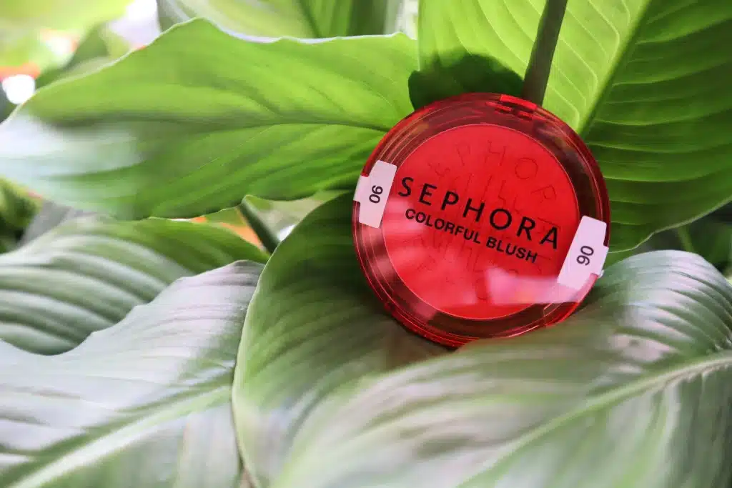 Rozświetlający róż w pudrze Sephora Collection Colorful Blush 06 Tropical Dawn na tle zielonych liści skrzydłokwiatu