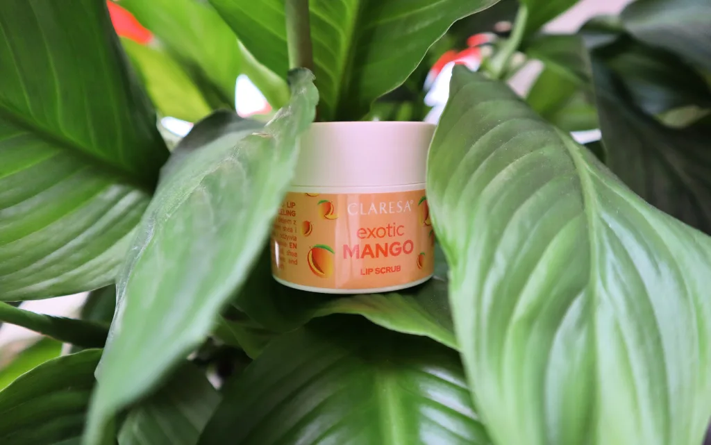 Opakowanie peelingu do ust  Claresa exotic mango na tle zielonej rośliny 