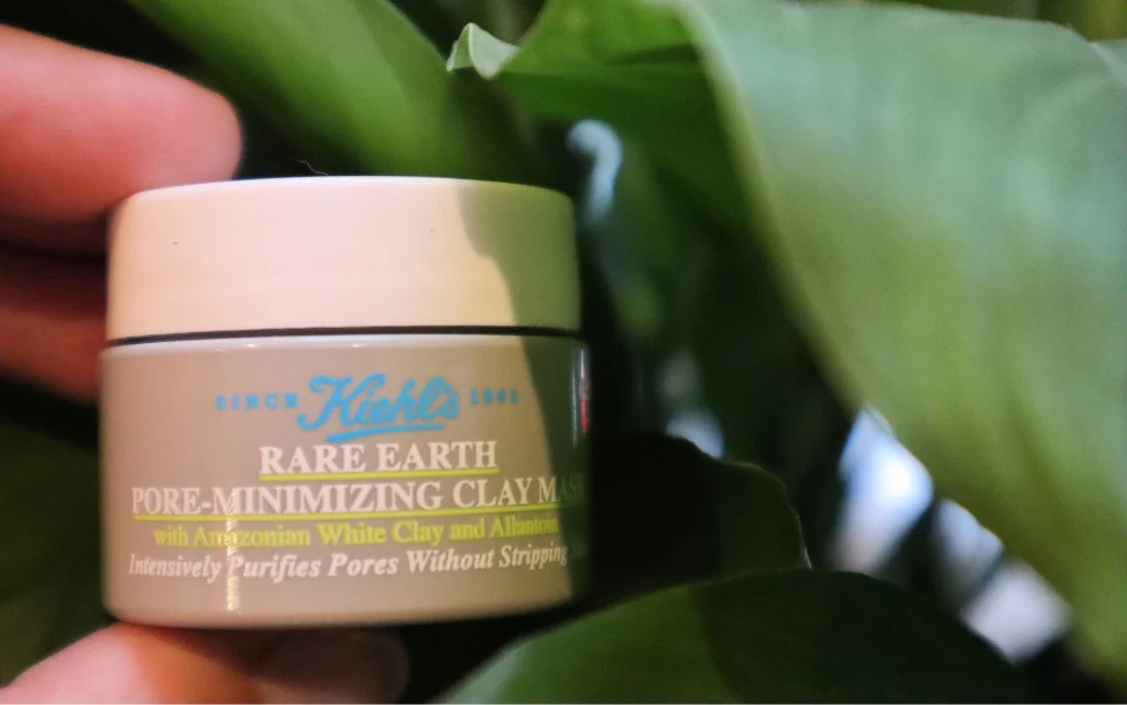 Maseczka z glinki Kiehl's Rare Earth Deep Pore Cleansing Mask  na tle zielonych liści kwiatu