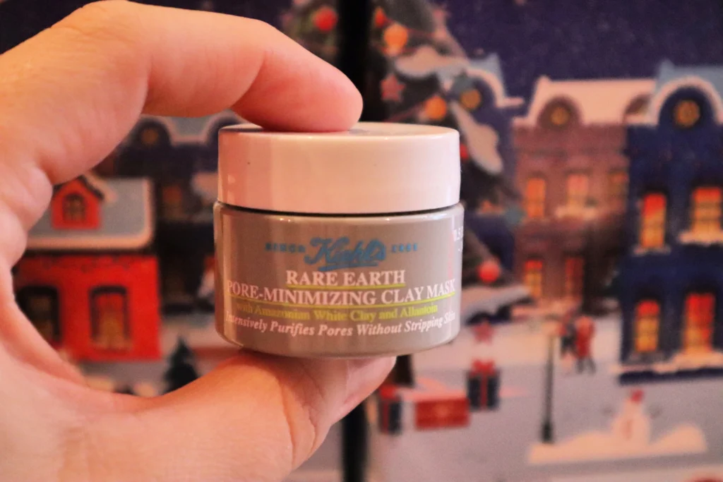  Kobiece dłonie trzymające opakowanie Kiehl's Rare Earth Deep Pore Cleansing Mask  