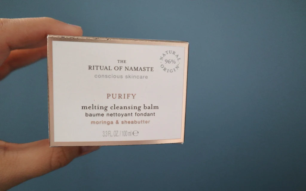 Rituals Namaste Melting Cleansing Balm w kobiecej dłoni na niebieskim tle