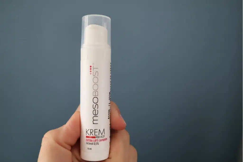 :Krem pod oczy z retinolem 0,5% mesoBoost trzymany w kobiecej dłoni, niebieskie tło