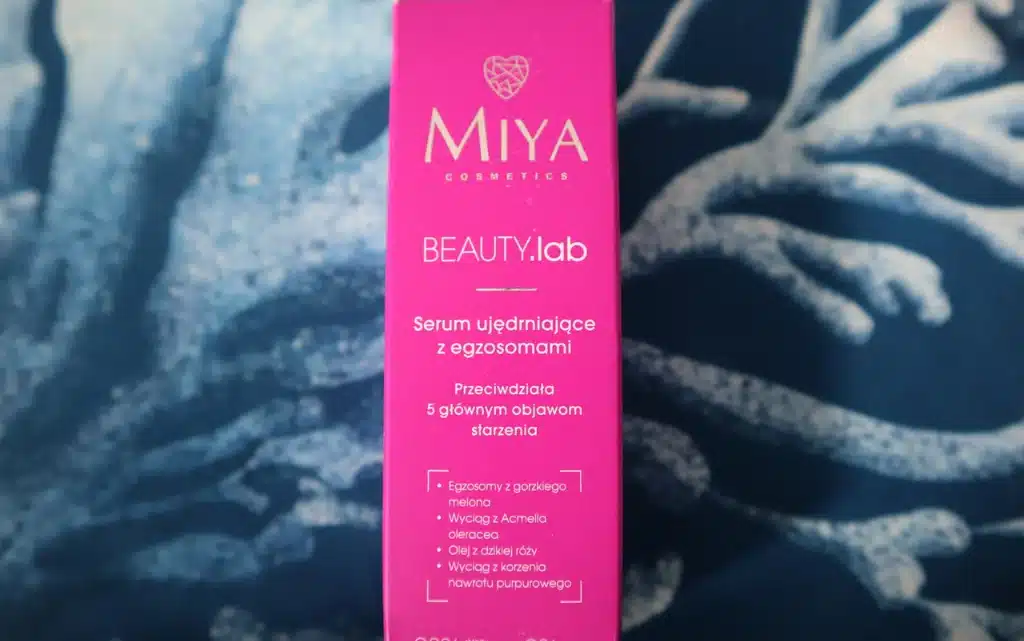 Tekturowe opakowanie serum ujędrniające z egzosomami Miya Cosmetics BEAUTY.lab  na tle niebieskiej poduszki
