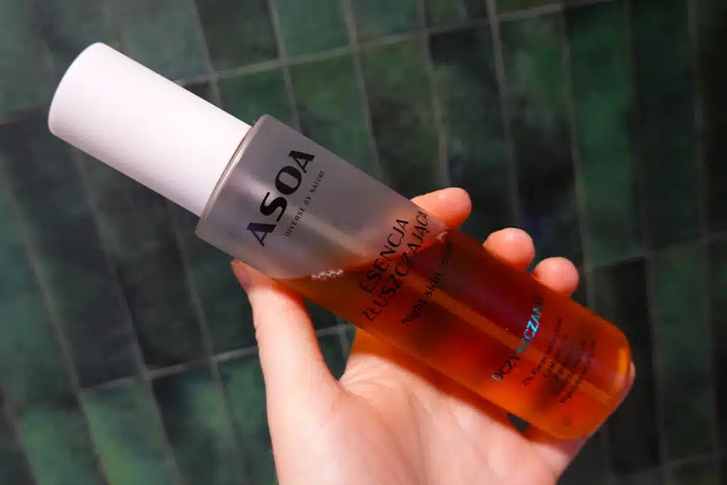 Esencja złuszczająca ASOA night skin repair w kobiecej dłoni, w tle zielone płytki w łazience