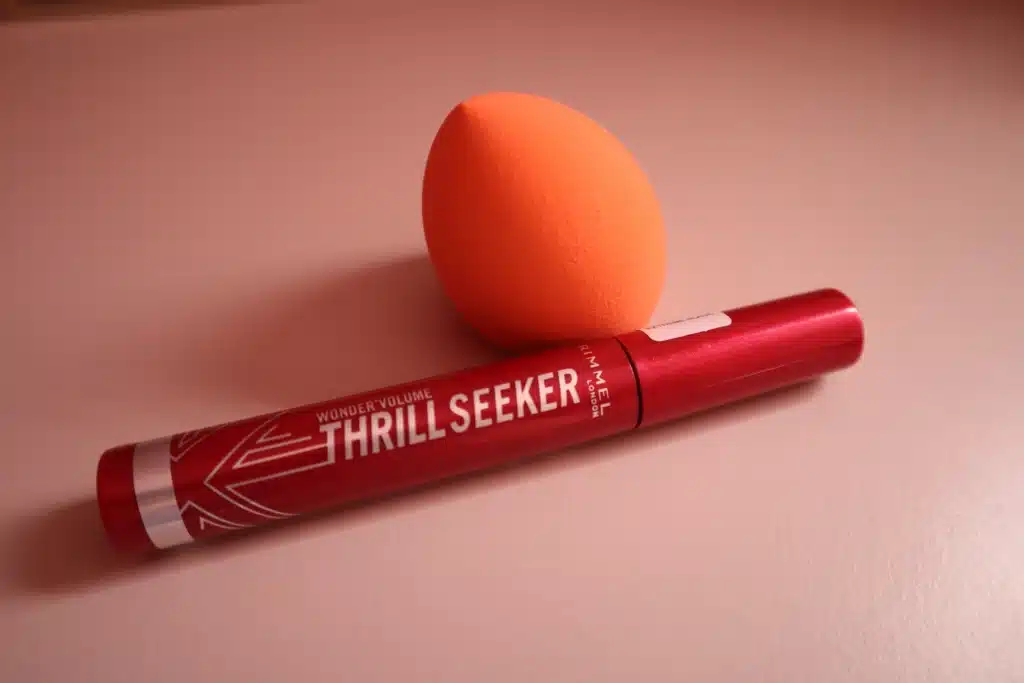 Rimmel Volume Thrill Seeker wydłużający i zwiększający objętość tusz do rzęs obok gąbki do makijażu 