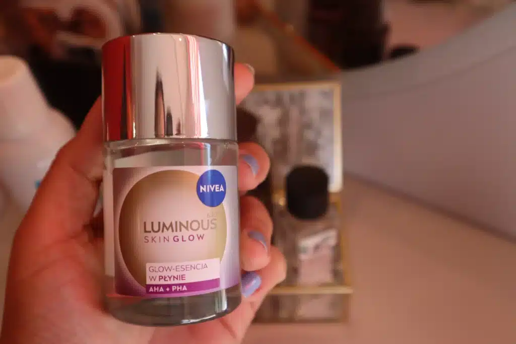 NIVEA Luminous630 glow-esencja w płynie peeling mikrozłuszczający trzymany w kobiecej dłoni 